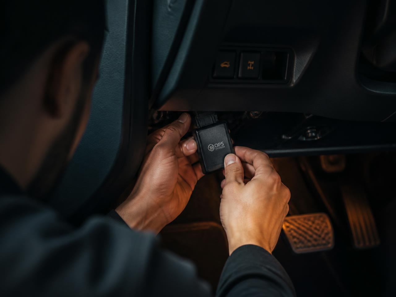 Técnico instalando rastreador veicular no painel do carro